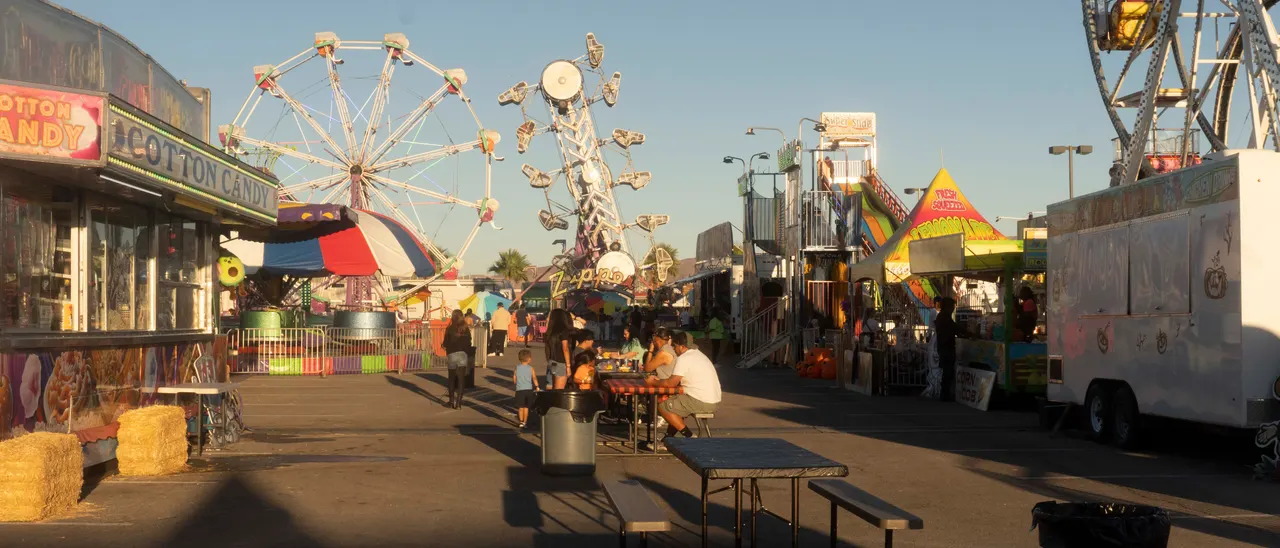 Looking down the midway in late afternoon: the Ferris wheel, food trailers and picnic tables