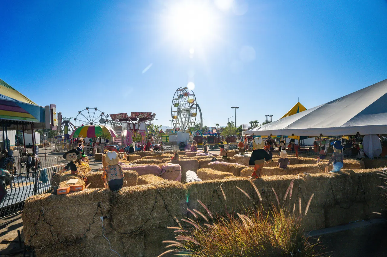 The hay-bale maze in daylight, with the Ferris wheel and carnival tents behind it