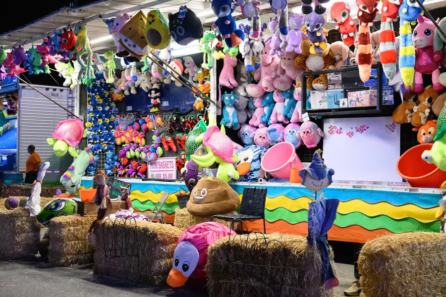 A midway game tent with prizes and hay bales in daylight