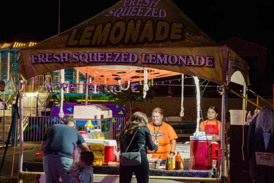 Families ordering at the Fresh Squeezed Lemonade stand at night
