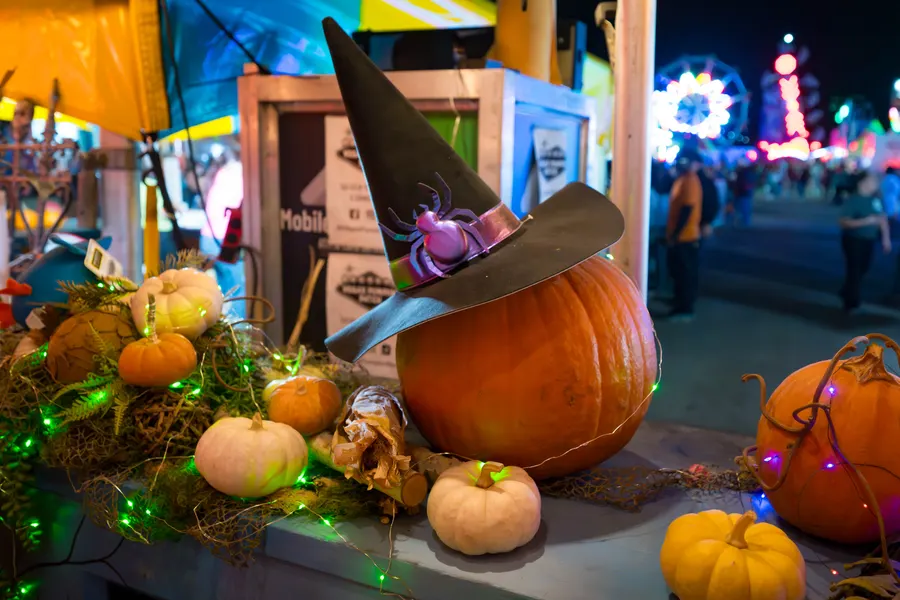 A witch-hat pumpkin with the midway behind it
