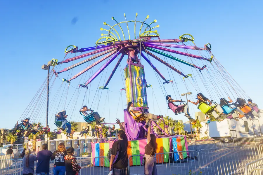 Riders flying out on the YoYo swing ride while families watch from the fence