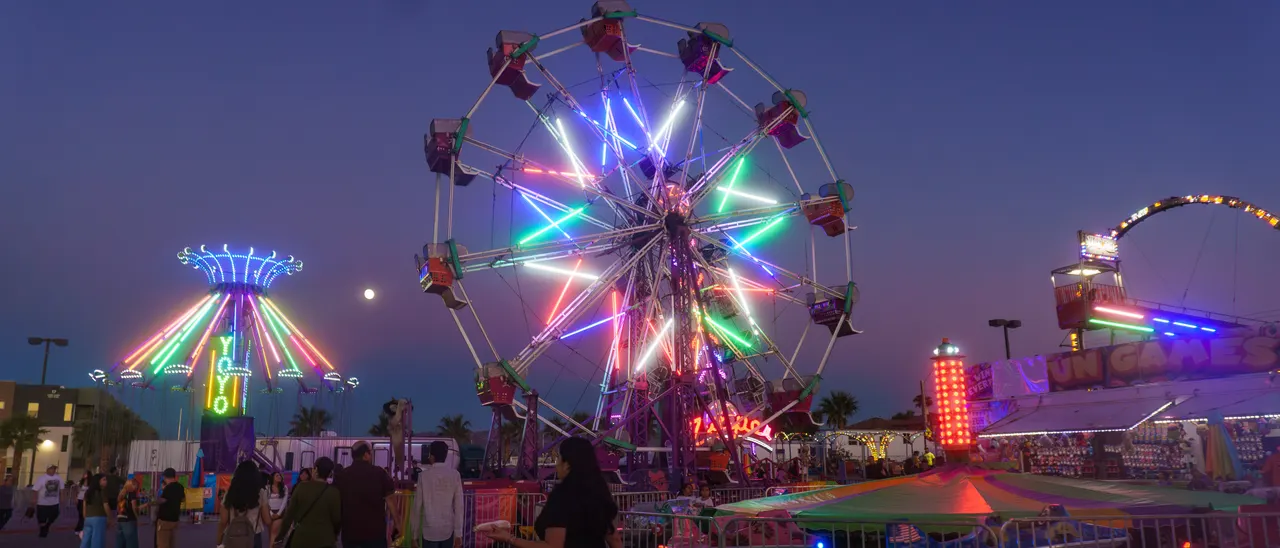 The swing ride mid-spin at dusk with families watching from the fence