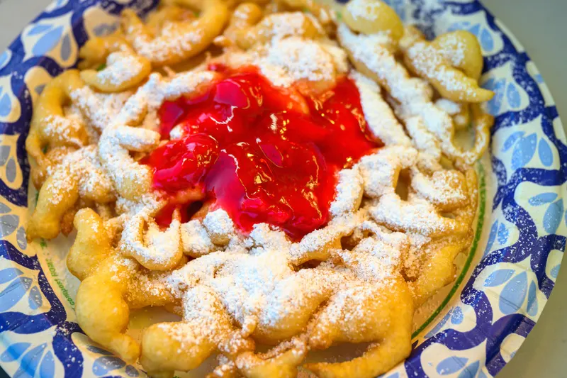 A funnel cake topped with strawberries and powdered sugar
