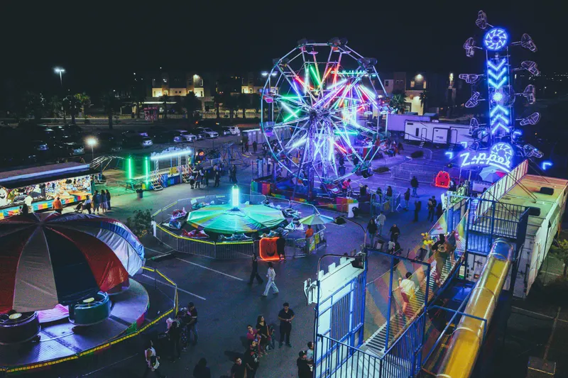 Carnival rides lit up at night, seen from above, with the Las Vegas valley behind them